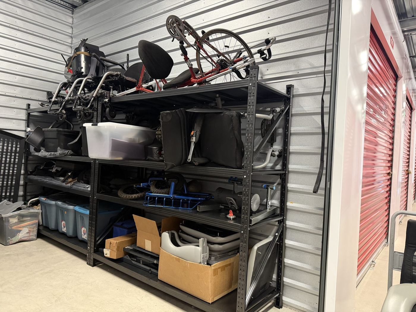 Handcycle, wheelchair frames, and bins on Everyday Abilities Equipment Library shelving.