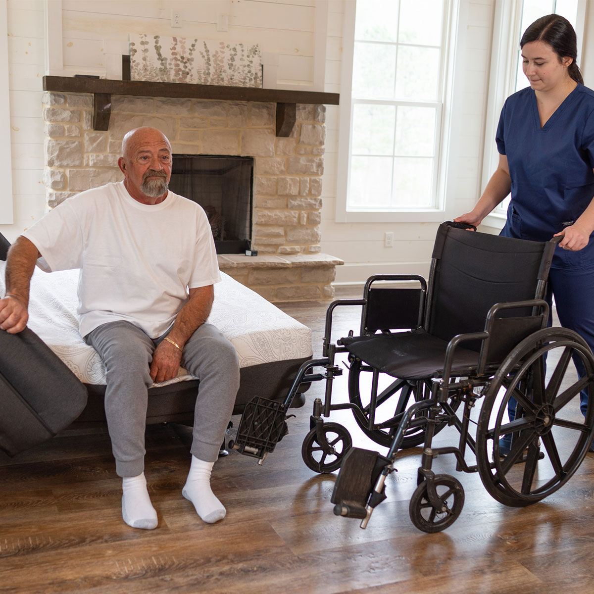 Flexabed Hi-Low adjustable bed lowered beside a wheelchair for a seated transfer in a bedroom.